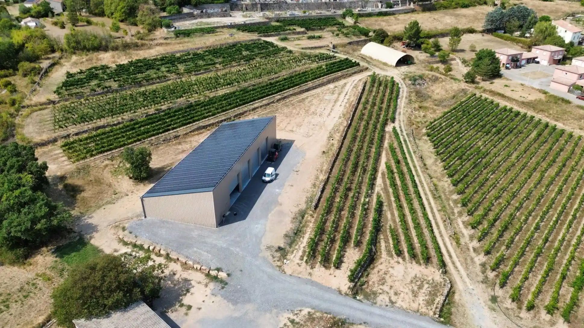 Photo aérienne d'un beau hangar agricole solaire Triangle Énergie au milieu des vignes