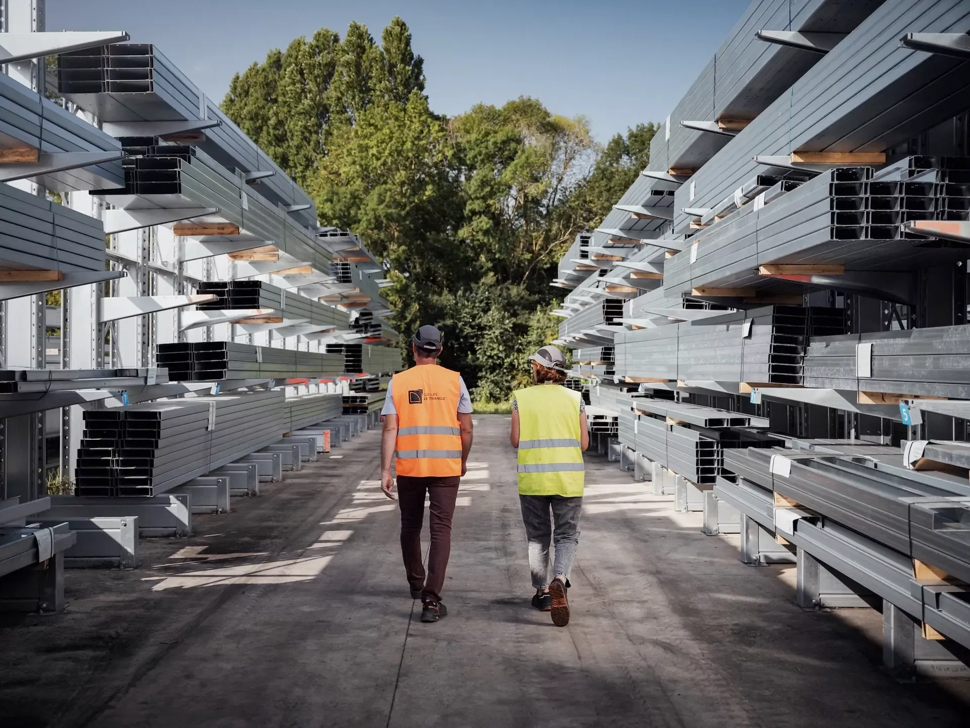 2 hommes de dos dans une allée du stock de matériaux du Groupe Le Triangle, leader du photovoltaïque